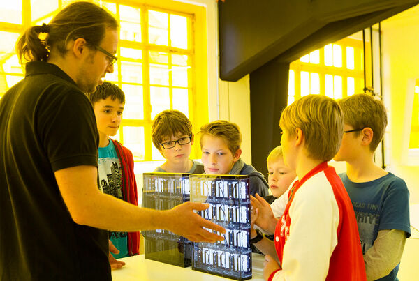 Ein Museumspädagoge erklärt Schülern eines der interaktiven Exponate.
