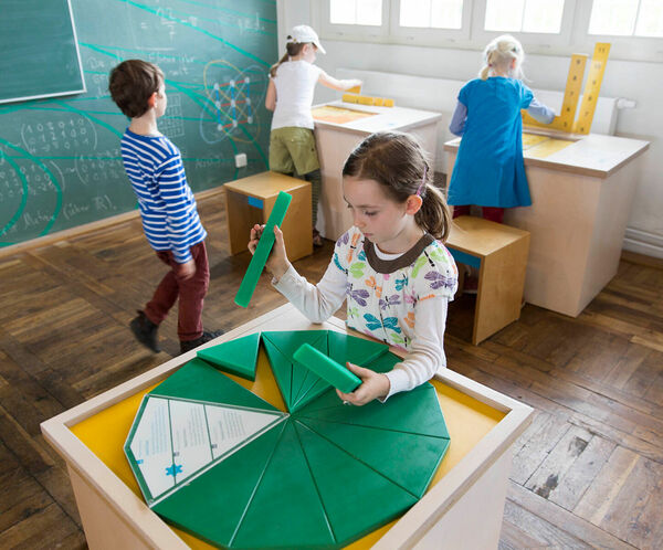 Ein Mädchen erkundet ein interaktives Exponat im Erlebnisland Mathematik.